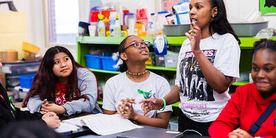teacher/school leader talking with students around a table