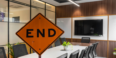 image of a board meeting room overlaid with a street sign that reads "End"