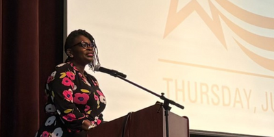 a black woman in a dress standing at a podium on a stage